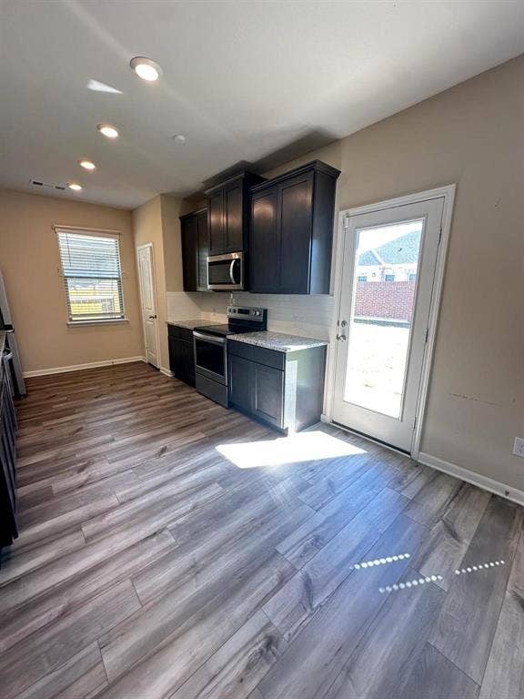 1707 Cotton Blossom Lane, Princeton, TX 75407 Modern kitchen featuring wood-finish flooring, dark cabinetry, light-toned countertops, and recessed lighting
