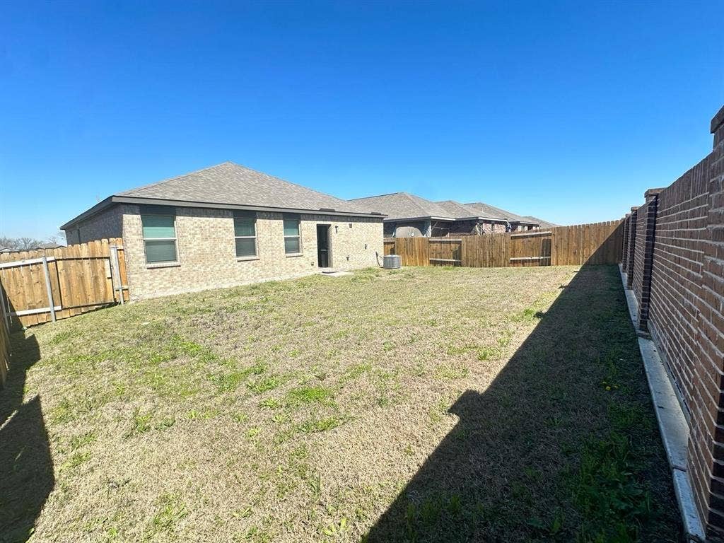 1707 Cotton Blossom Lane, Princeton, TX 75407 Fenced backyard featuring a mix of wood privacy fencing and a brick privacy wall