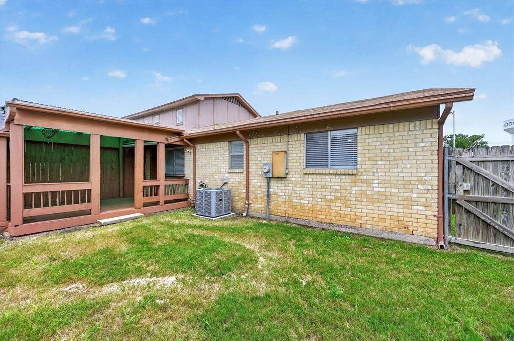 1012 Plover Lane, Arlington, TX 76015 Expansive grassy area featuring a covered porch with wood railing, a brick exterior, and a wooden privacy fence