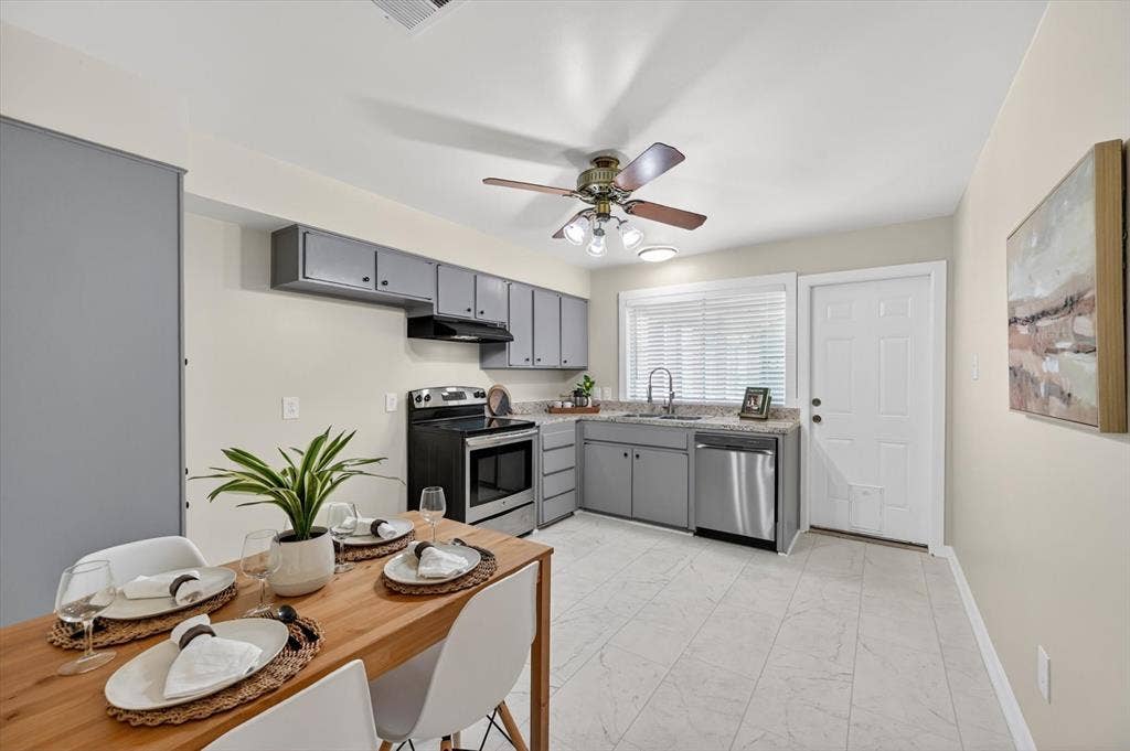 1012 Plover Lane, Arlington, TX 76015 Kitchen and dining area featuring light-toned walls, wood-finish dining table, and tile flooring