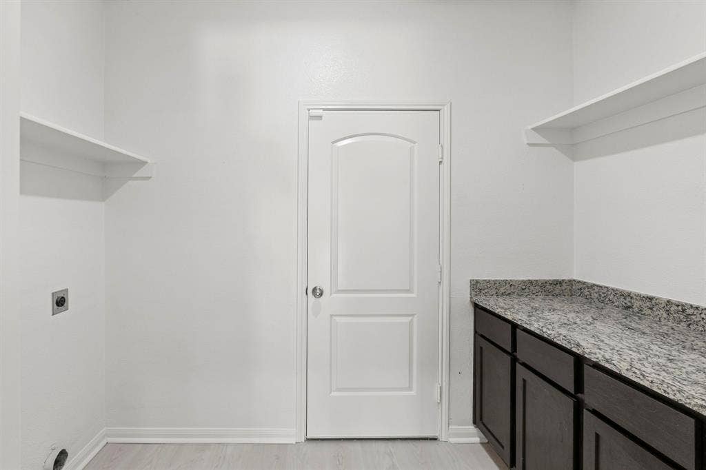 1516 Kinglet Street, DeSoto, TX 75115 Utility space featuring dark wood-finish cabinetry, a speckled countertop, and two built-in storage shelves