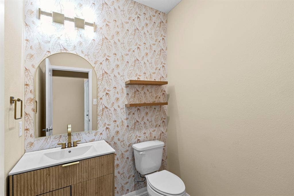1516 Kinglet Street, DeSoto, TX 75115 Bathroom vanity featuring a white countertop with integrated sink, gold-finish faucet, and a mirror with an arched top