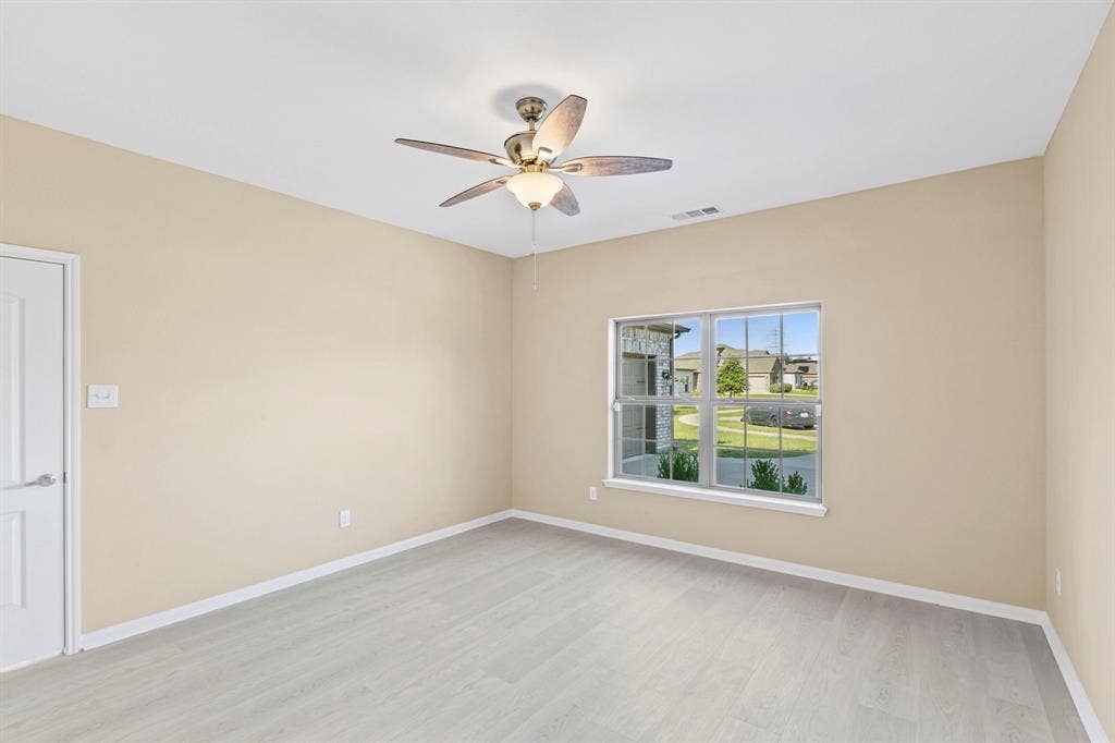 1516 Kinglet Street, DeSoto, TX 75115 Spacious room featuring light wood-finish flooring, a ceiling fan with integrated lighting, and a white interior door