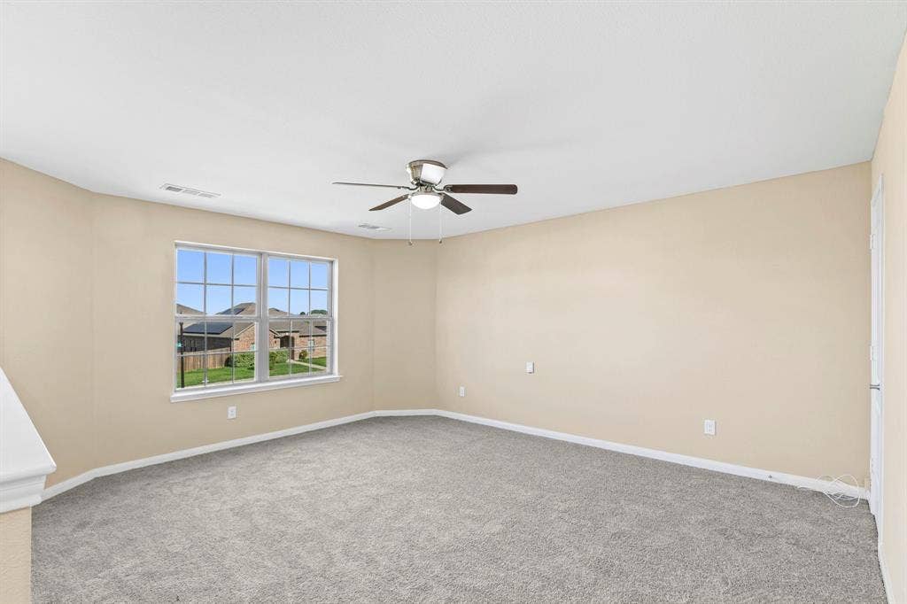 1516 Kinglet Street, DeSoto, TX 75115 Carpeted interior space featuring neutral wall tones, a ceiling fan with integrated lighting, and a multi-pane window