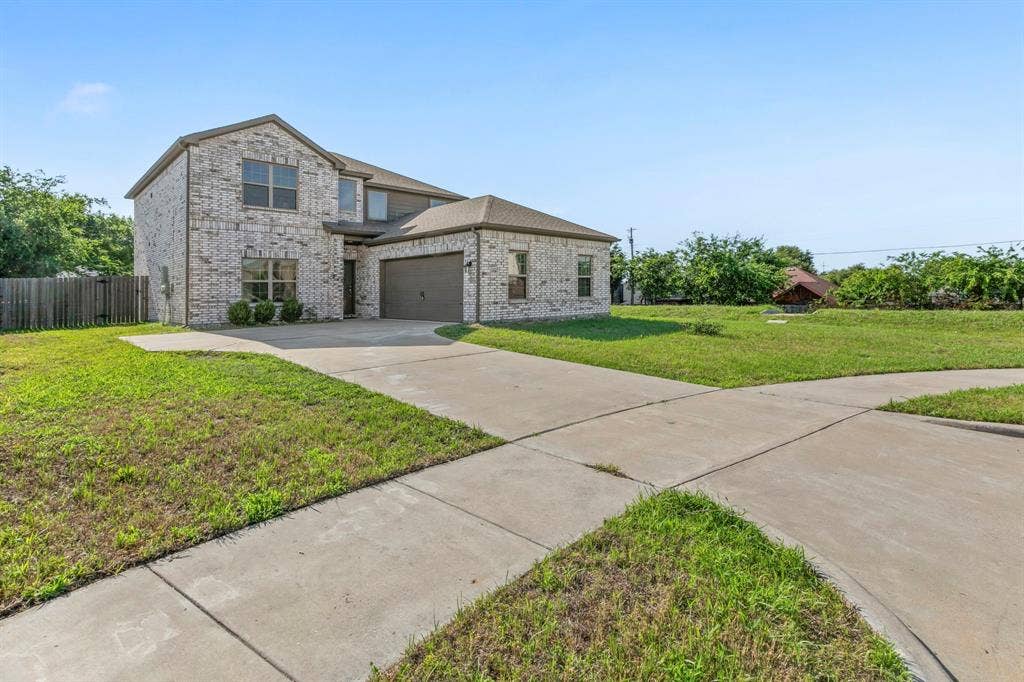 1516 Kinglet Street, DeSoto, TX 75115 Two-story brick exterior featuring a multi-pane window design, an attached garage, and a concrete driveway