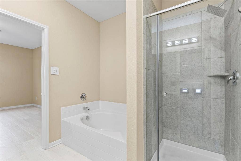 1516 Kinglet Street, DeSoto, TX 75115 Bathroom featuring a tiled walk-in shower with a glass enclosure, a built-in shower shelf, and a square rainfall showerhead