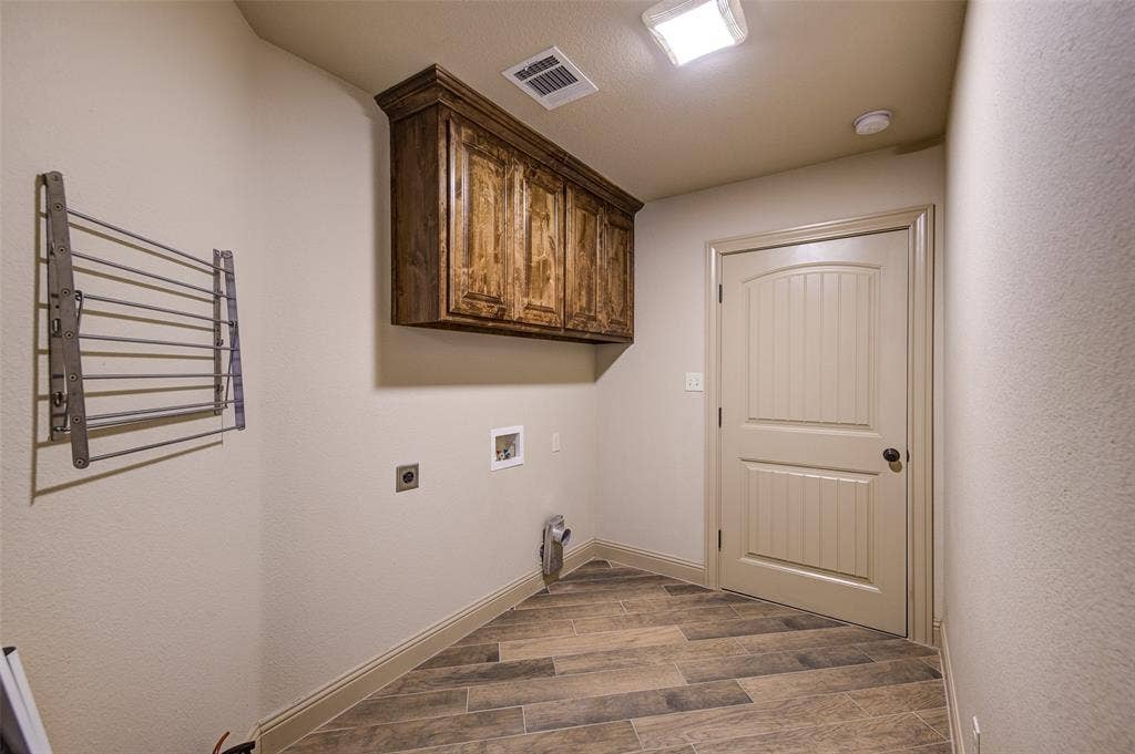 245 Fm 407 W, Argyle, TX 76226 Downstairs Laundry area featuring electric dryer hookup, washer hookup, dark wood-style flooring, and cabinet space with door to 2 car garage