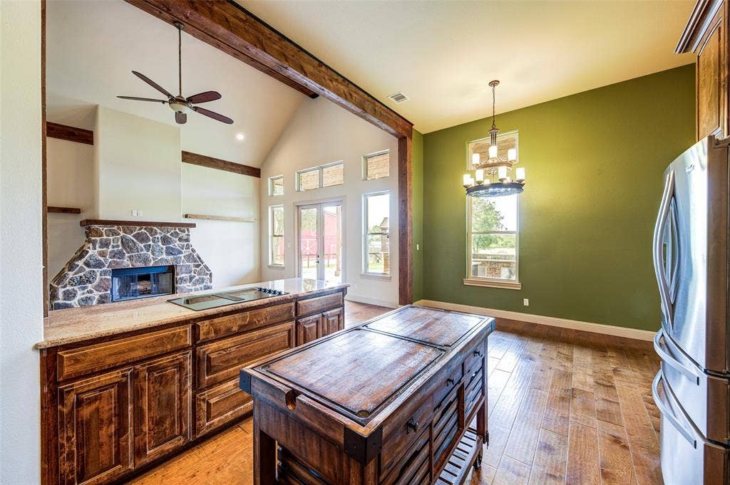 245 Fm 407 W, Argyle, TX 76226 Kitchen with an island, freestanding refrigerator, light wood-style floors, a fireplace, ceiling fan, and a chandelier in dining area