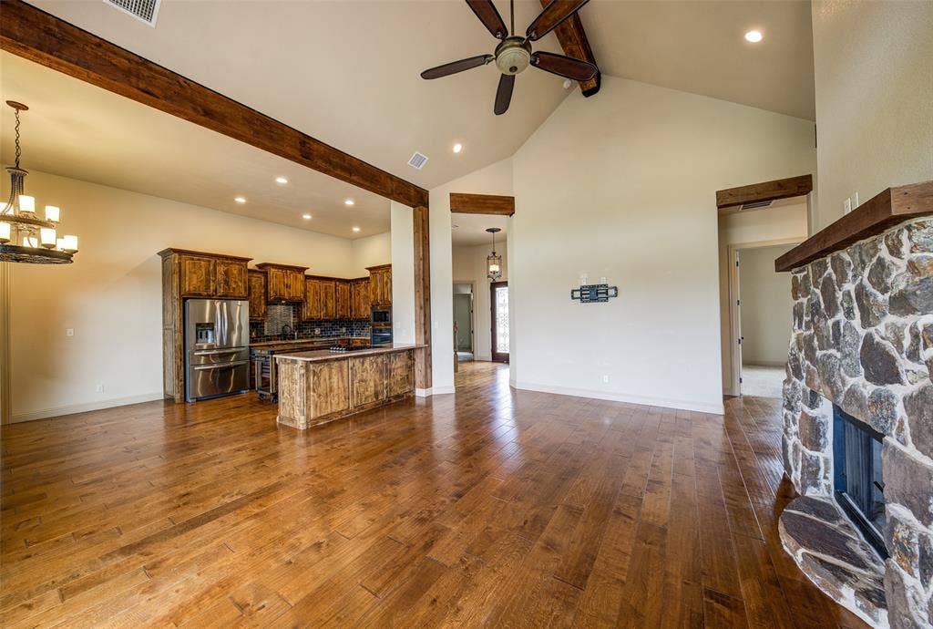 245 Fm 407 W, Argyle, TX 76226 Living area with a ceiling fan, beam ceiling, a stone fireplace, and dark wood-type flooring
