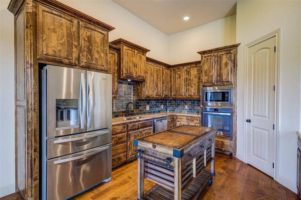 245 Fm 407 W, Argyle, TX 76226 Kitchen with an island, stainless steel appliances, decorative backsplash, wood-type flooring, recessed lighting, and light stone countertops