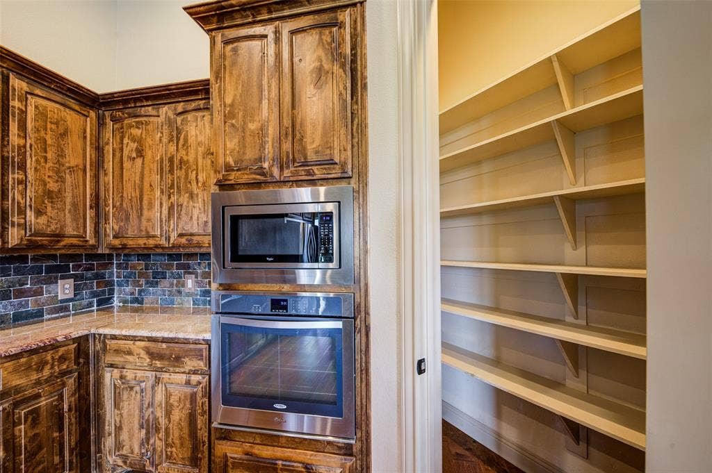 245 Fm 407 W, Argyle, TX 76226 Kitchen with stainless steel appliances, large pantry, light stone countertops, and tasteful backsplash