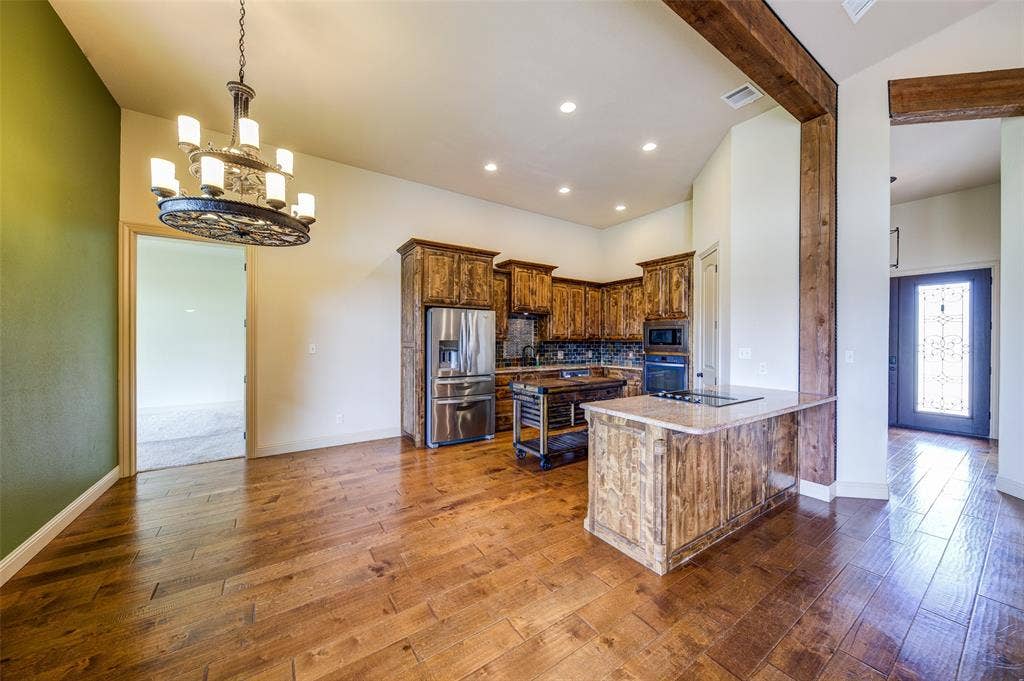 245 Fm 407 W, Argyle, TX 76226 Kitchen and Dining area featuring a chandelier, black appliances, dark wood-style flooring, tasteful backsplash, and a peninsula