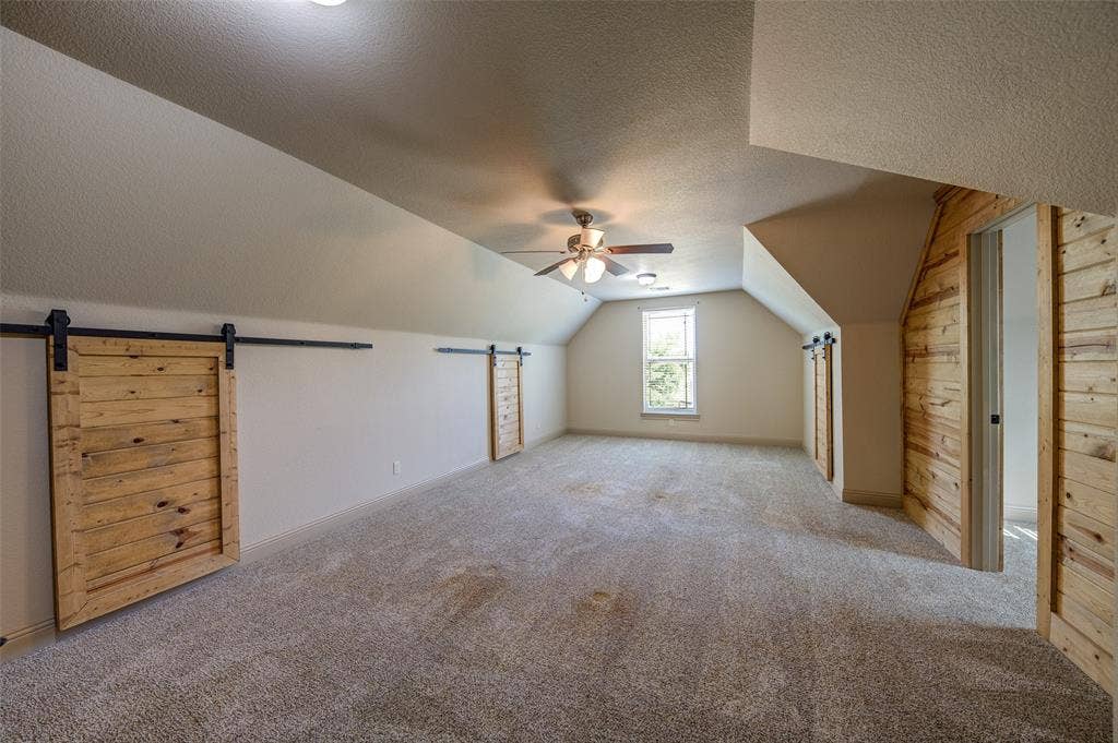 245 Fm 407 W, Argyle, TX 76226 Upstairs Additional living space featuring new carpet flooring, a ceiling fan, a textured ceiling, vaulted ceiling, lots of storage and wooden wall