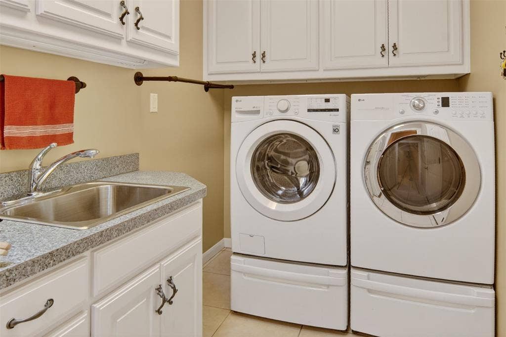 Spacious laundry room with sink and an abundance of storage.