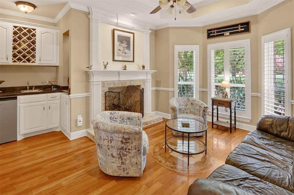 Formal living area with fireplace, wet bar, wood shutters, and wood flooring.