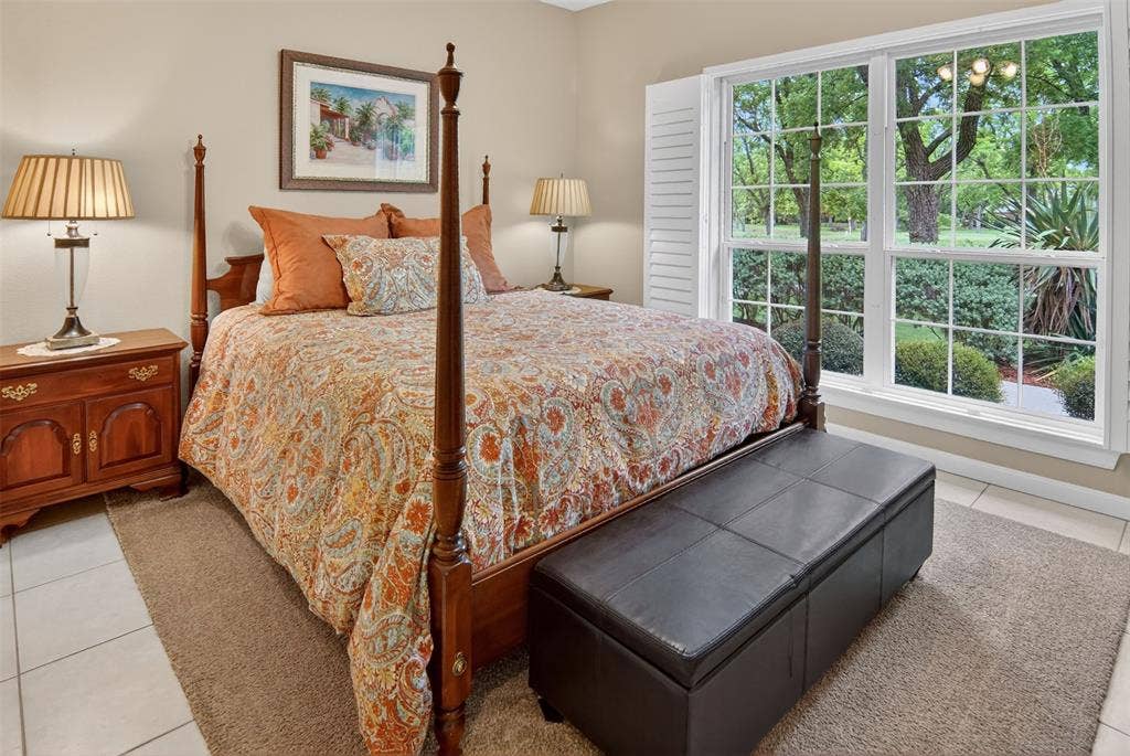 Guest bedroom with tile flooring and large windows with lovely view of back yard.