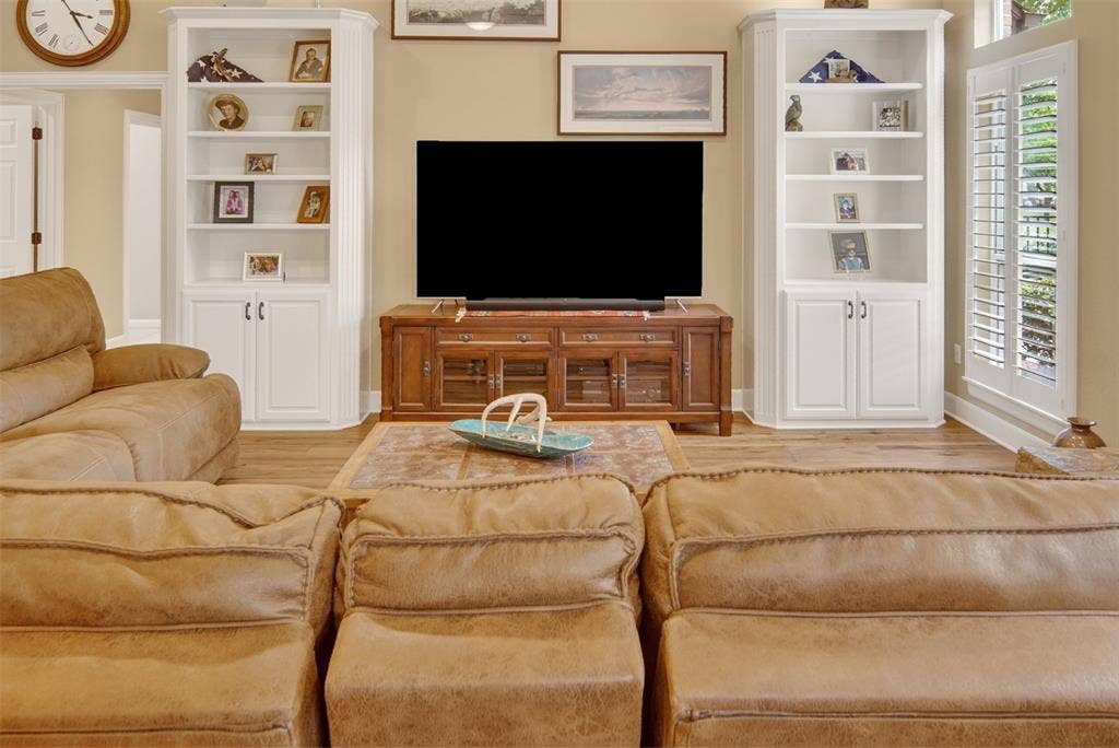 Additional view of family room with built ins, wood shutters, and wood flooring.