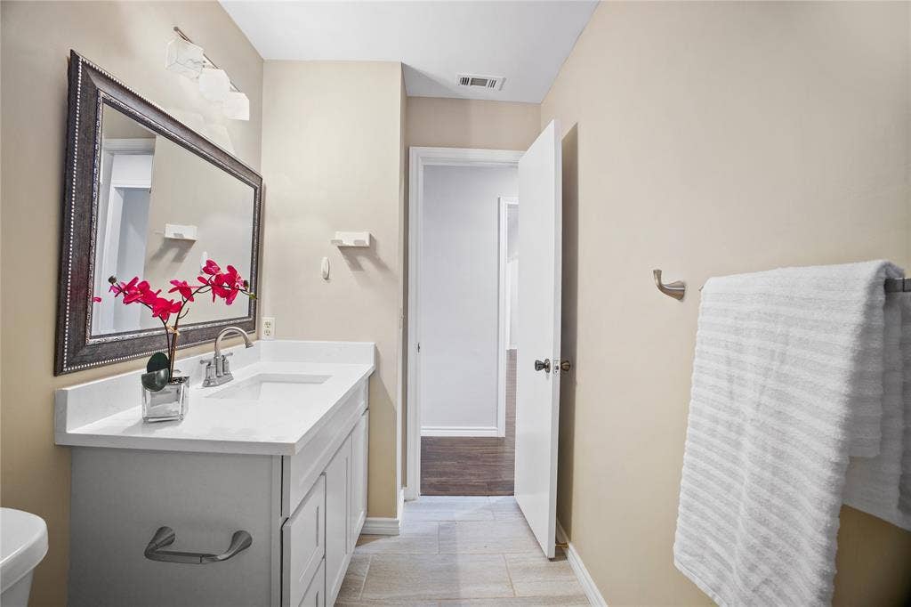 3228 Anchor Drive, Plano, TX 75023 Bathroom featuring a white vanity with an integrated sink, polished chrome faucet, and a large framed mirror