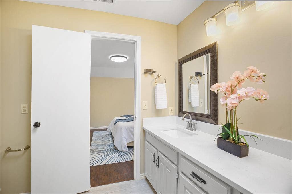 3228 Anchor Drive, Plano, TX 75023 Bathroom vanity featuring a single undermount sink with a chrome faucet, light-colored countertop, and light gray cabinetry