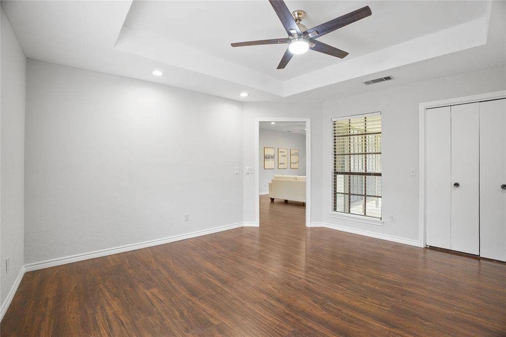 3228 Anchor Drive, Plano, TX 75023 Spacious room featuring wood-finish flooring, a tray ceiling with a ceiling fan, recessed lighting, and a bay window with blinds