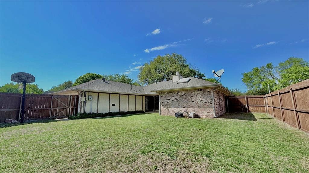 3228 Anchor Drive, Plano, TX 75023 Expansive backyard featuring a manicured lawn, full wood fencing, and a brick exterior home with a shingled roof