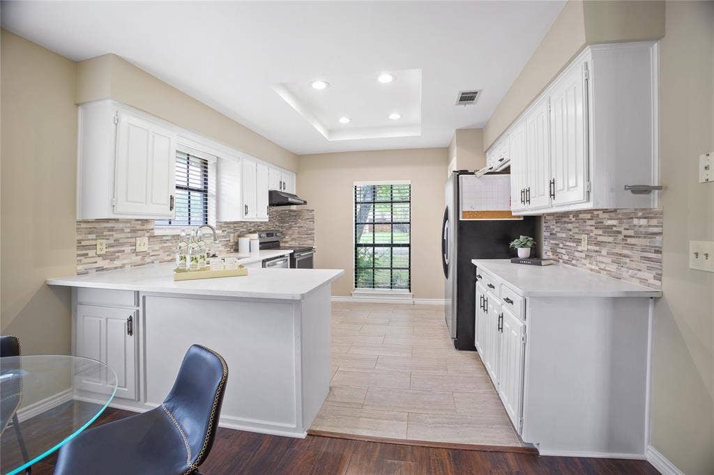 3228 Anchor Drive, Plano, TX 75023 Kitchen featuring white cabinetry with dark hardware, a mosaic tile backsplash, and light-toned countertops