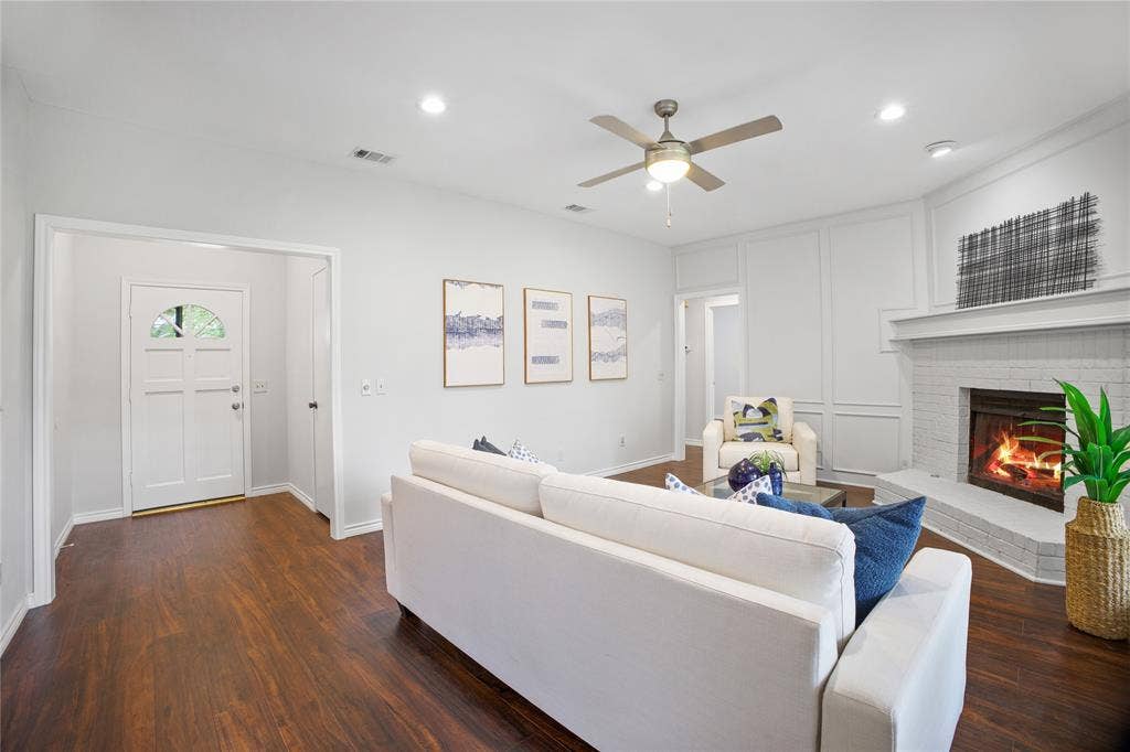 3228 Anchor Drive, Plano, TX 75023 Spacious living area featuring wood-finish flooring, a white brick corner fireplace with mantle, recessed lighting, and a ceiling fan
