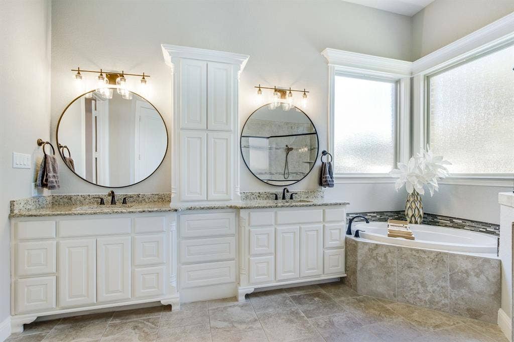 Bathe in luxury with these dual vanities, updated mirrors and lighting!