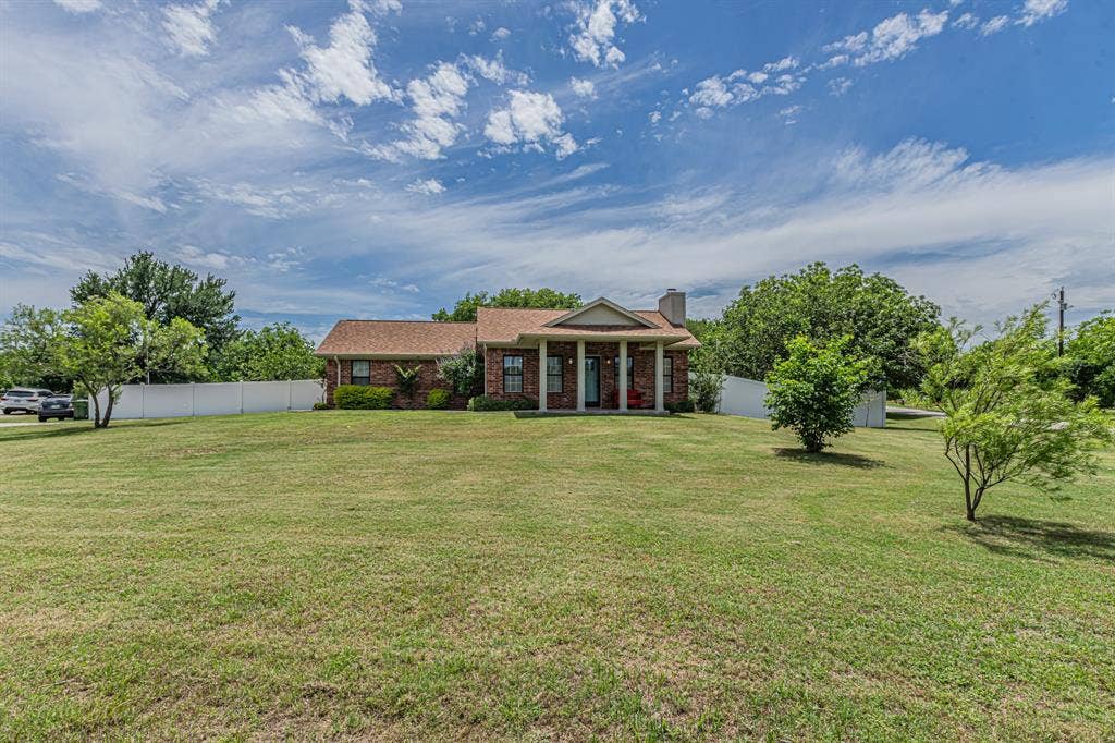204 S Spring Branch Trail, Springtown, TX 76082 Brick residence featuring a columned front porch and a prominent chimney