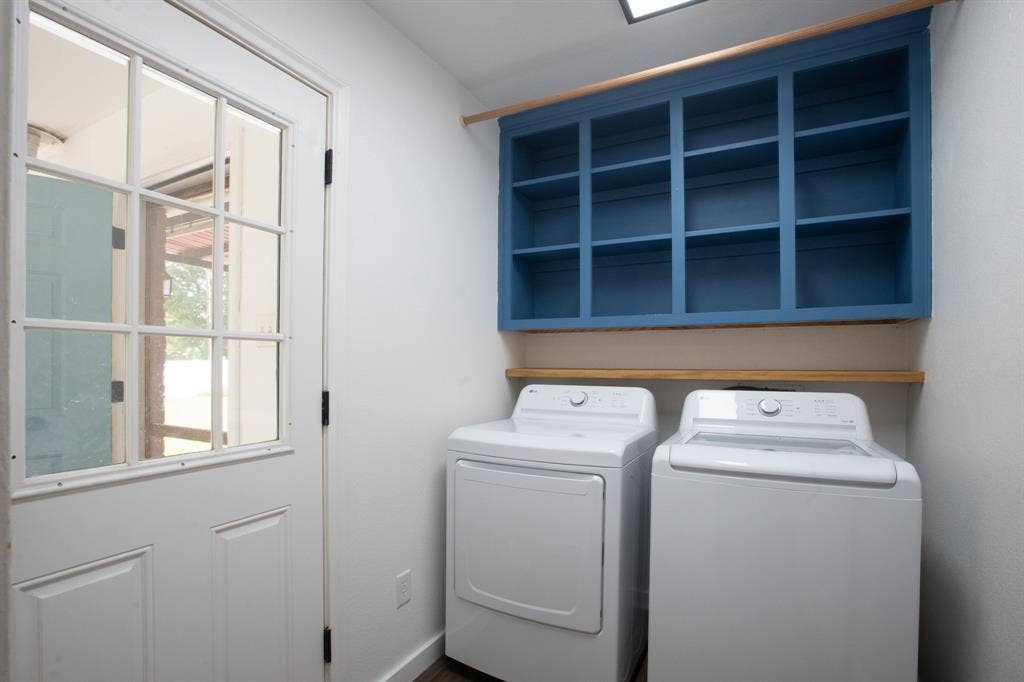 204 S Spring Branch Trail, Springtown, TX 76082 Dedicated laundry area featuring a white paneled door with windowpanes, a blue built-in storage cabinet with wooden trim, and a wooden shelf
