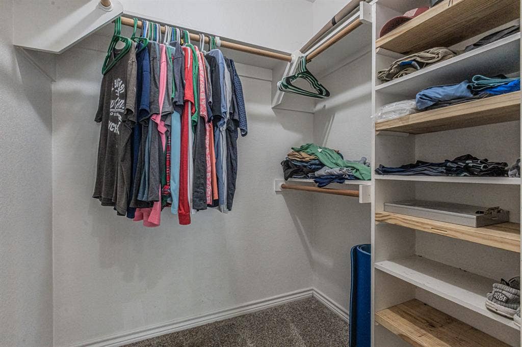 204 S Spring Branch Trail, Springtown, TX 76082 Built-in closet system featuring multiple hanging rods, white-painted shelving, and wood-finish shelving