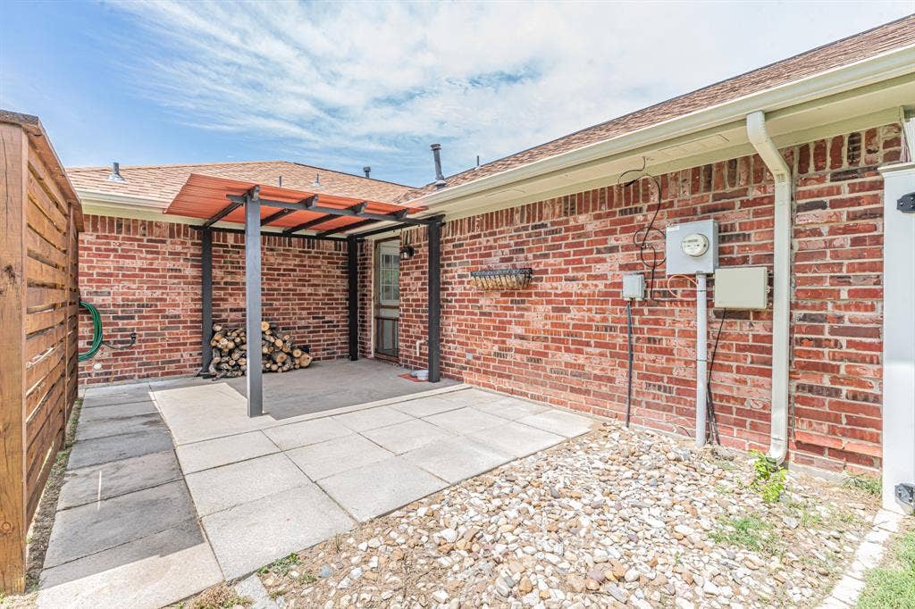 204 S Spring Branch Trail, Springtown, TX 76082 Brick exterior featuring a covered patio, a privacy fence, stone ground cover, and exterior lighting