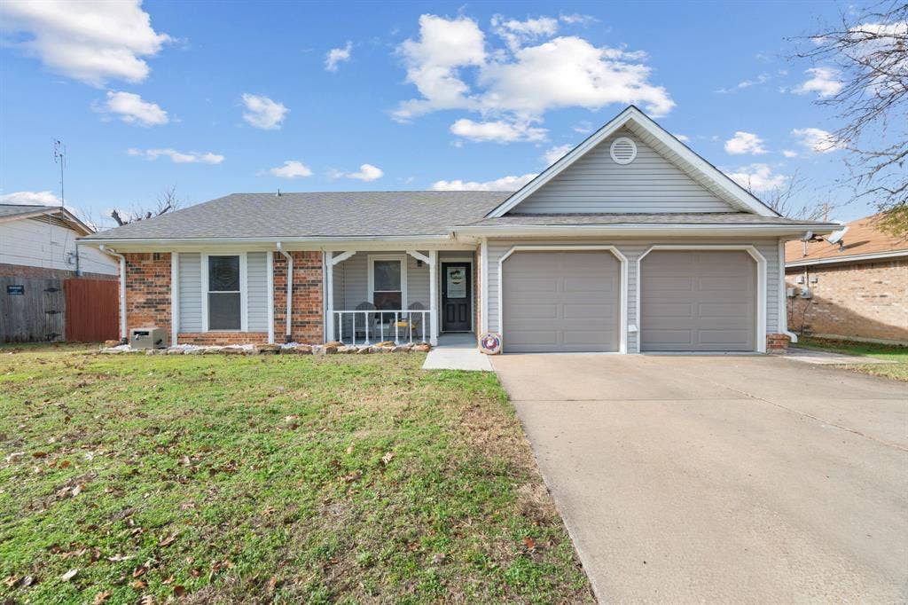 7629 Cedarhill Road, Watauga, TX 76148 Traditional exterior featuring brick and light gray siding, a two-car garage with matching garage doors, a concrete driveway, and a covered front porch with white railings