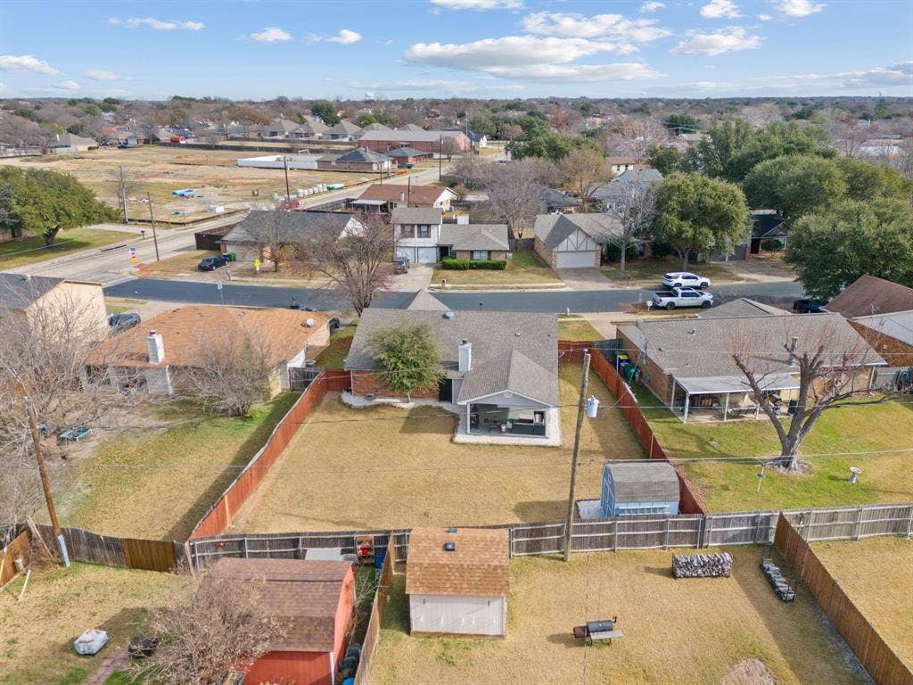 7629 Cedarhill Road, Watauga, TX 76148 Expansive backyard featuring a wood fence, multiple storage sheds, and mature landscaping