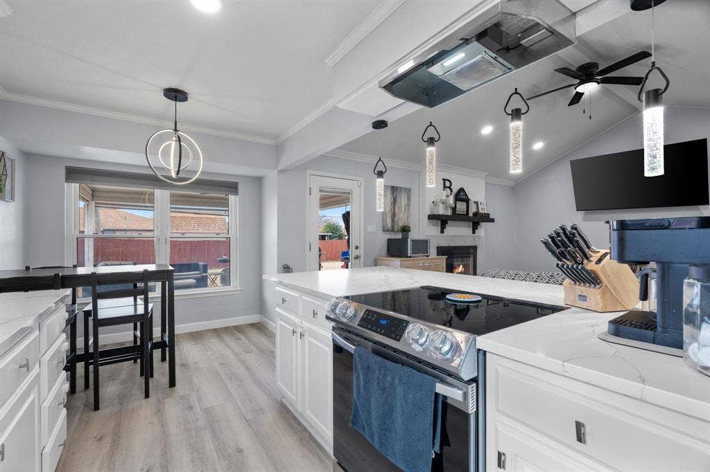 7629 Cedarhill Road, Watauga, TX 76148 Kitchen featuring white cabinetry, light-toned wood-finish flooring, white countertops, and a modern electric range