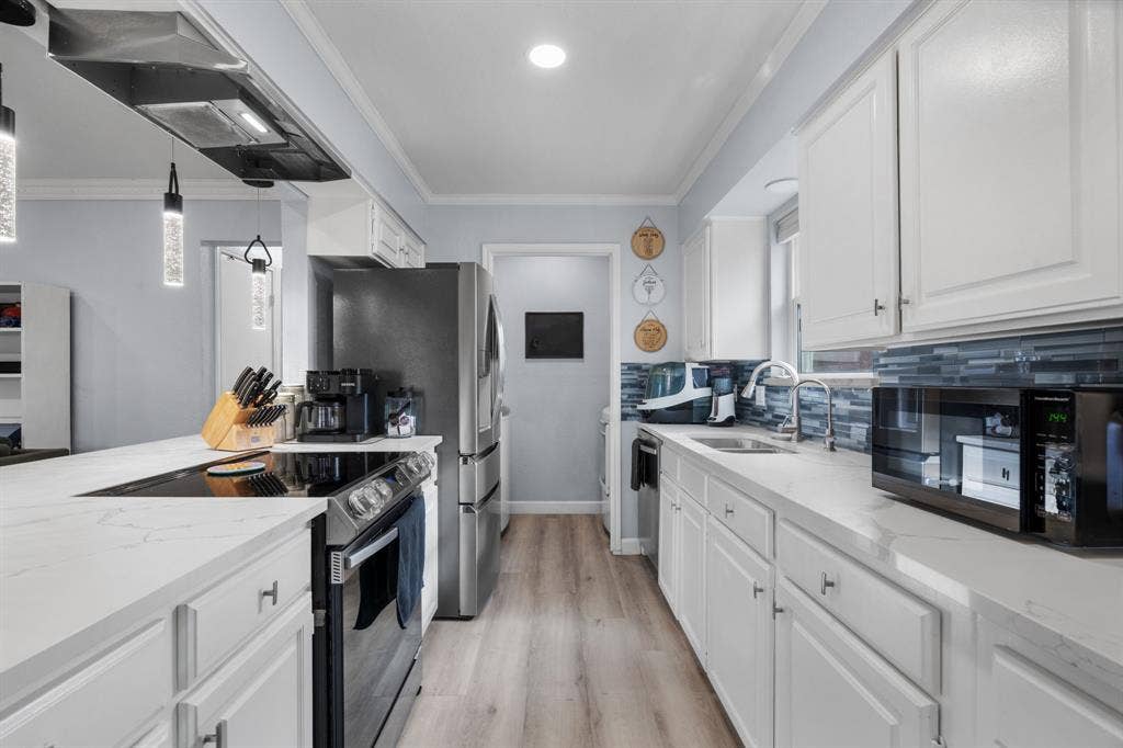 7629 Cedarhill Road, Watauga, TX 76148 Modern kitchen featuring white cabinetry, light-toned countertops, and a full suite of stainless steel appliances including a refrigerator and range