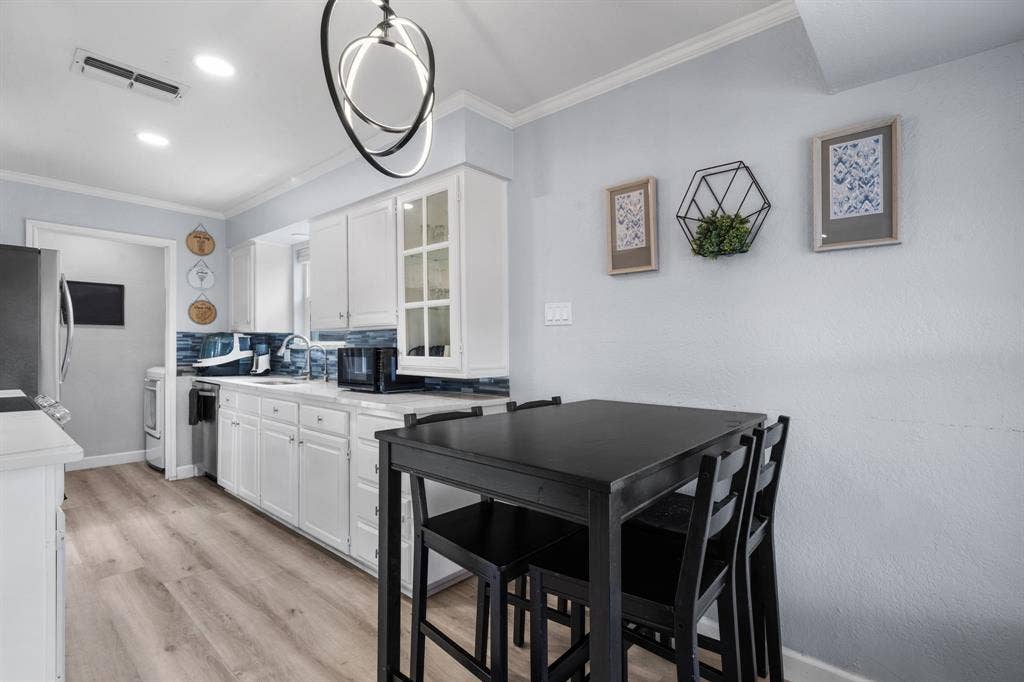 7629 Cedarhill Road, Watauga, TX 76148 Kitchen featuring white cabinetry with glass-front accents, light-tone wood-finish flooring, and a blue tile backsplash
