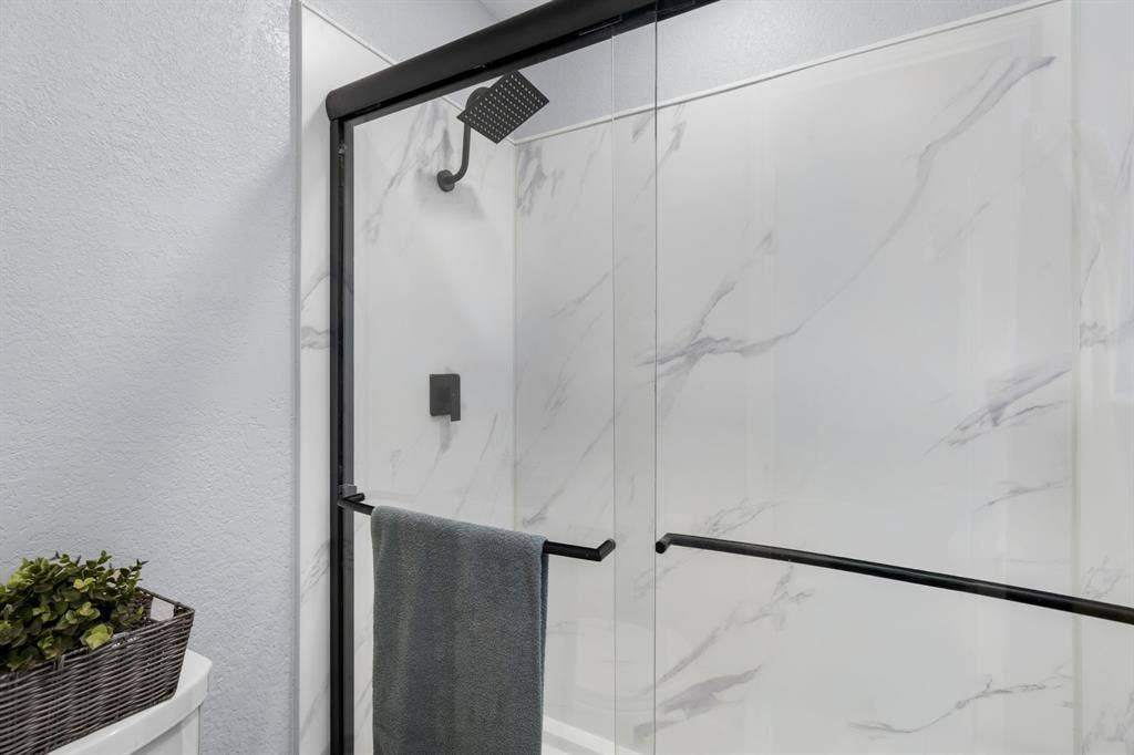 7629 Cedarhill Road, Watauga, TX 76148 Shower enclosure with clear glass panels, matte black framing, and a matte black rainfall showerhead