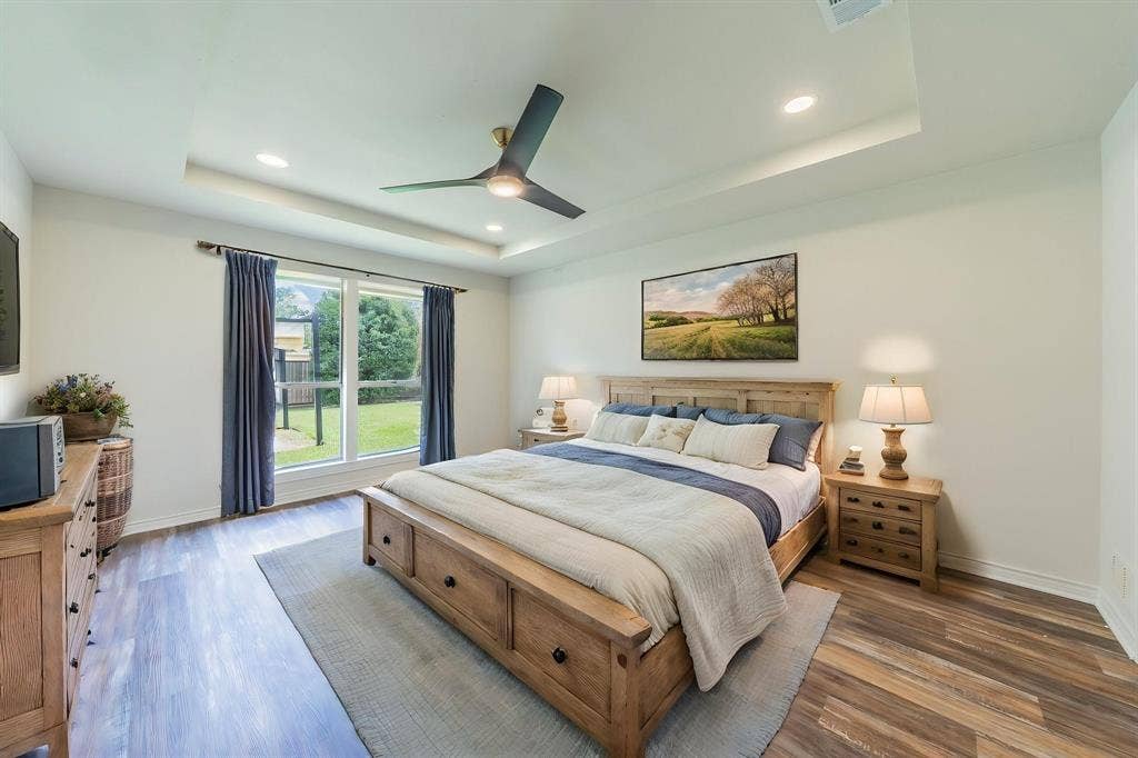 2212 Vickers Drive, Plano, TX 75075 Virtually Staged. Spacious room featuring wood-finish flooring, a tray ceiling with recessed lighting, and a modern ceiling fan