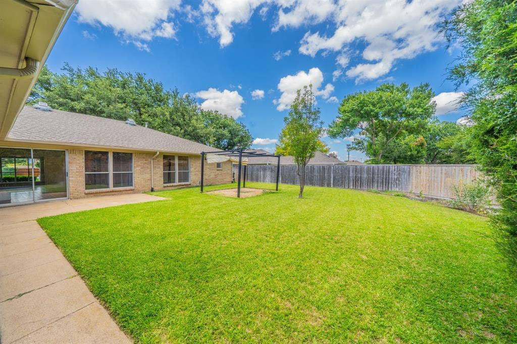 2212 Vickers Drive, Plano, TX 75075 Spacious backyard featuring a lush lawn, concrete patio, and a privacy fence