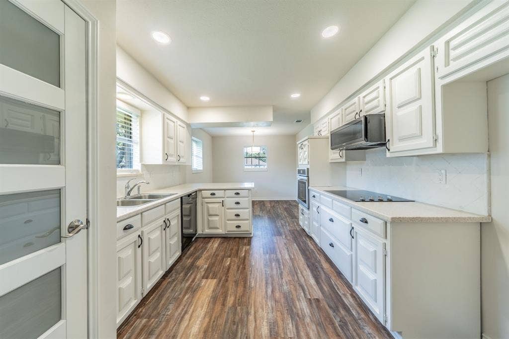 2212 Vickers Drive, Plano, TX 75075 Kitchen featuring wood-finish flooring, white cabinetry, integrated stainless steel double sink, light-colored countertops, and recessed lighting