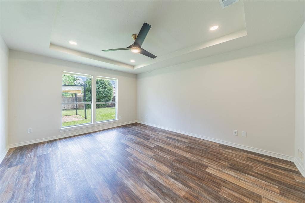 2212 Vickers Drive, Plano, TX 75075 Bright interior space featuring wood-finish flooring, a contemporary ceiling fan, and recessed lighting within a tray ceiling