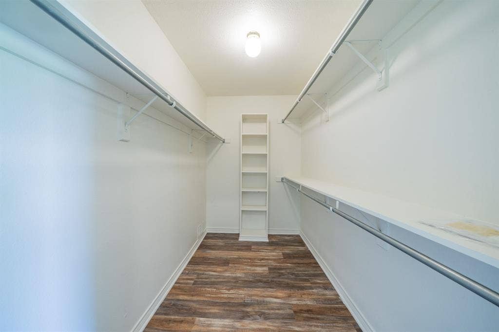 2212 Vickers Drive, Plano, TX 75075 Spacious walk-in closet featuring wood-finish flooring, white shelving, and dual hanging rods