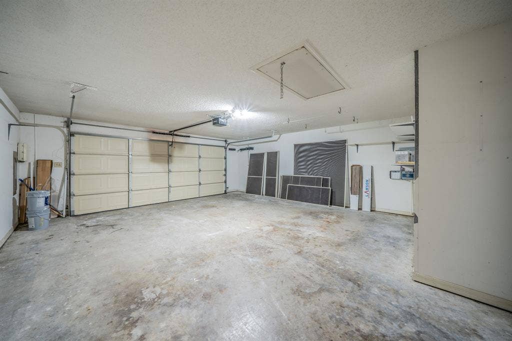 2212 Vickers Drive, Plano, TX 75075 Spacious garage with concrete flooring, overhead lighting, and a paneled garage door