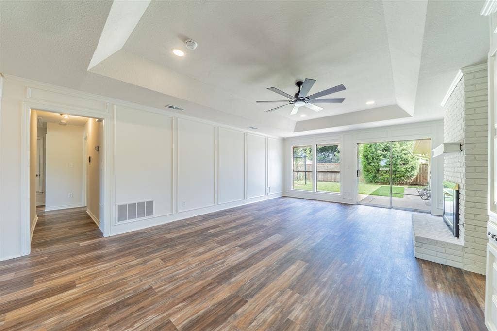 2212 Vickers Drive, Plano, TX 75075 Spacious living area featuring wood-finish flooring, white panel molding, and a tray ceiling with recessed lighting