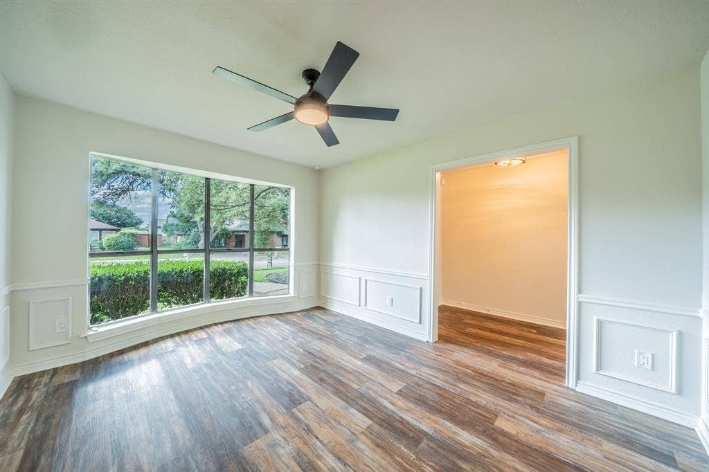 2212 Vickers Drive, Plano, TX 75075 Spacious interior room featuring a large curved bay window, wood-finish flooring, and wainscoting