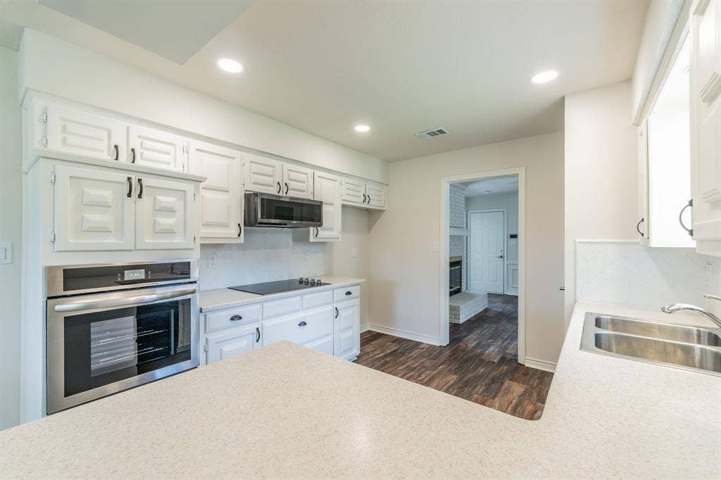 2212 Vickers Drive, Plano, TX 75075 Kitchen featuring white cabinetry, built-in stainless steel oven, electric cooktop, and dual basin sink
