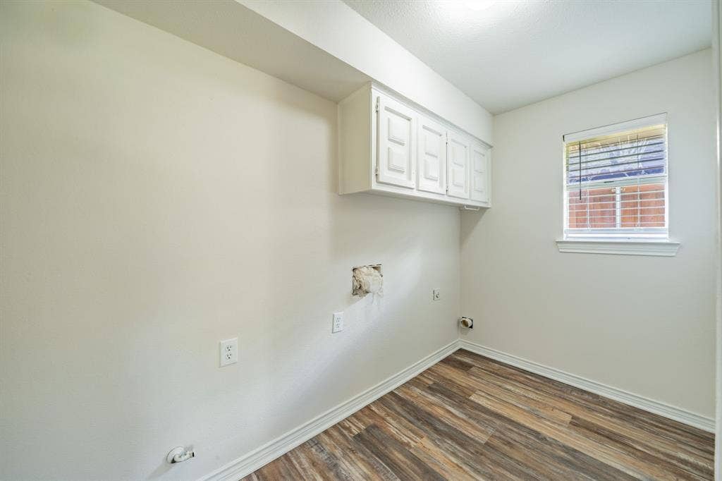2212 Vickers Drive, Plano, TX 75075 Laundry area with wood-finish flooring, white cabinetry, and a window with blinds