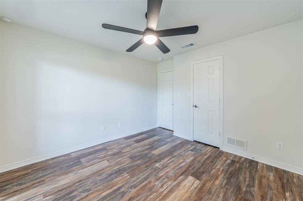 2212 Vickers Drive, Plano, TX 75075 Spacious room with wood-finish flooring, crisp white walls, and a contemporary ceiling fan