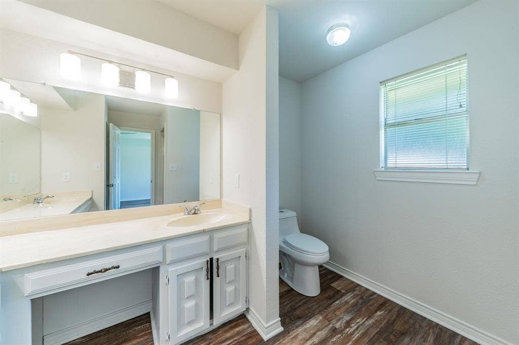 2212 Vickers Drive, Plano, TX 75075 Bathroom vanity featuring a double basin sink set in a light-toned countertop, extensive mirror, and multi-bulb vanity lighting